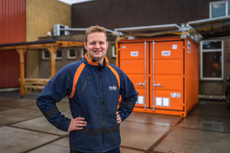Werknemer van Verno voor oranje zeecontainer met zonnepanelen